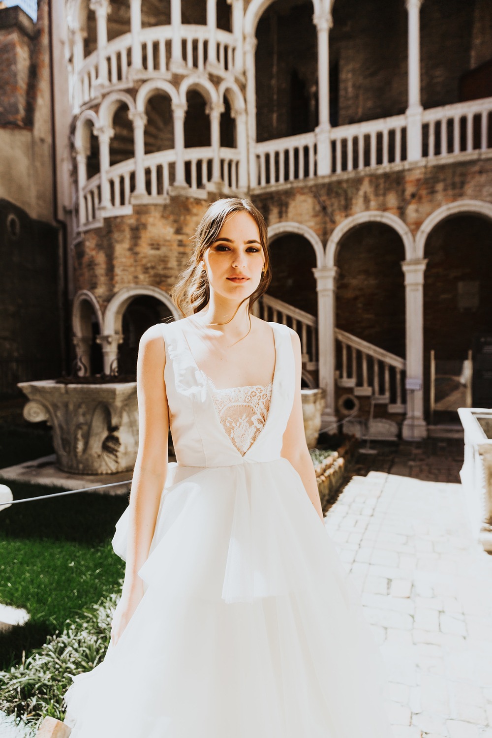 Elegant bride in a white dress poses in front of a historic building