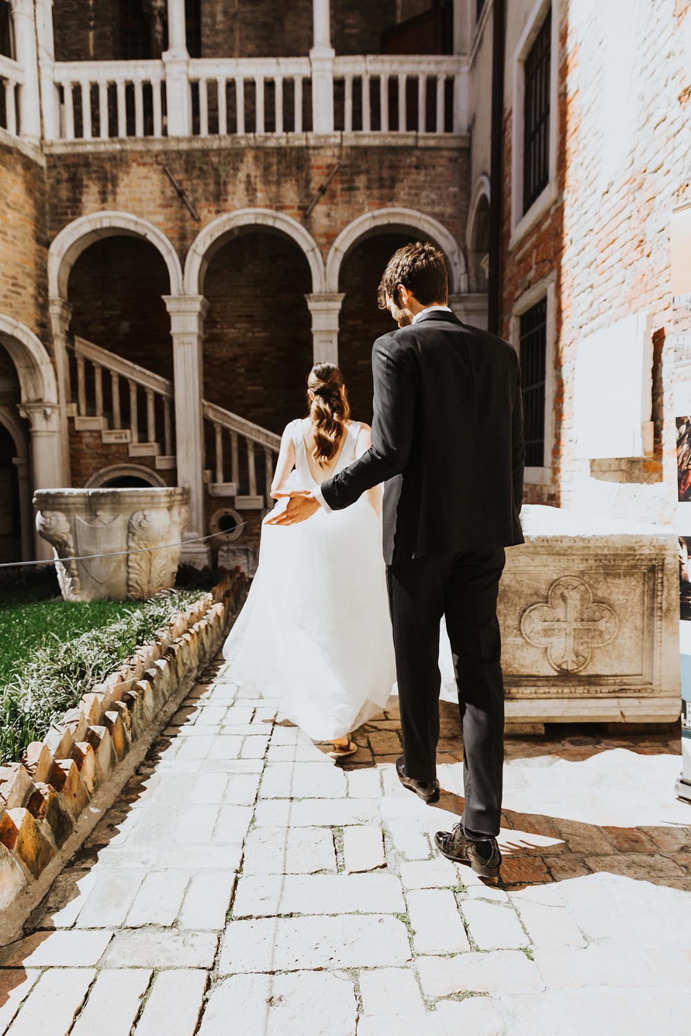 Elegant couple walking toward a wedding ceremony in a courtyard