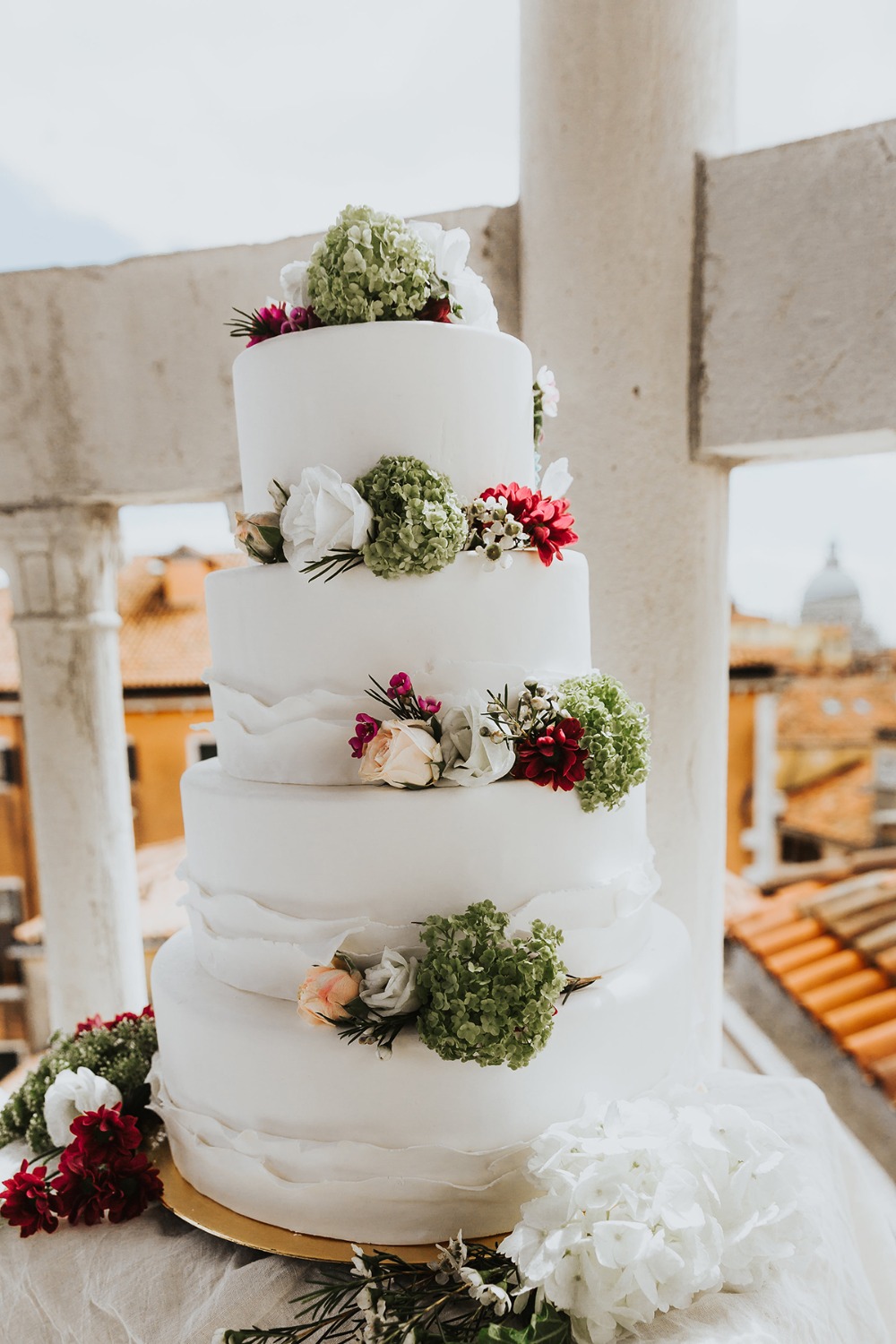 Elegant white wedding cake with flowers on a balcony