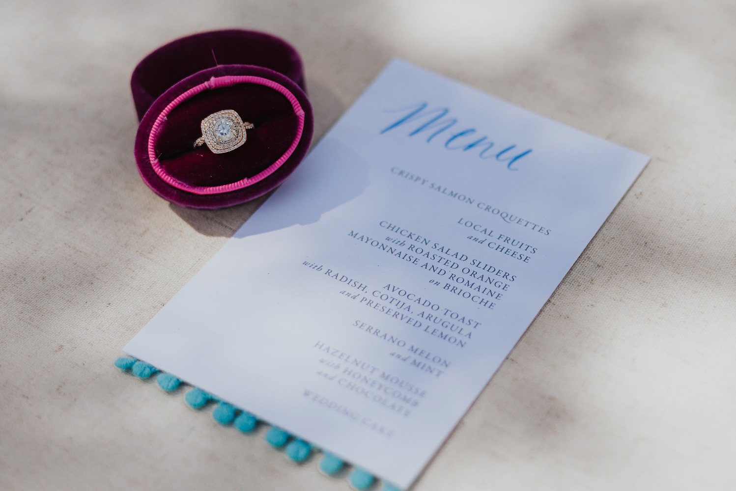 Engagement ring in velvet box next to elegant wedding menu