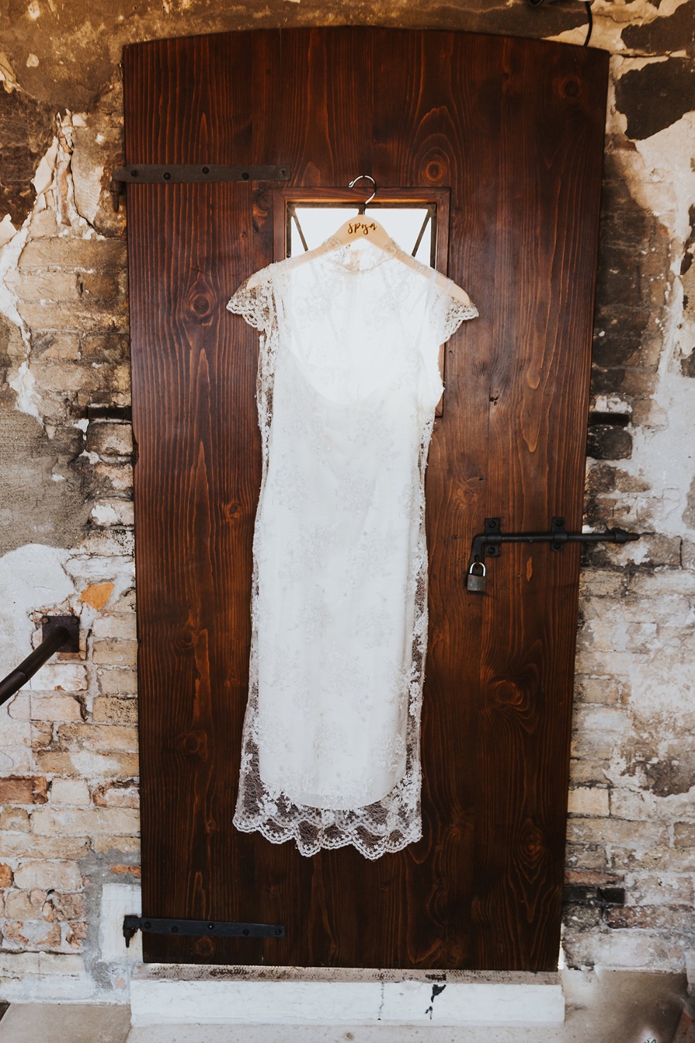 Wedding dress hanging on a rustic wooden door ready for the special day