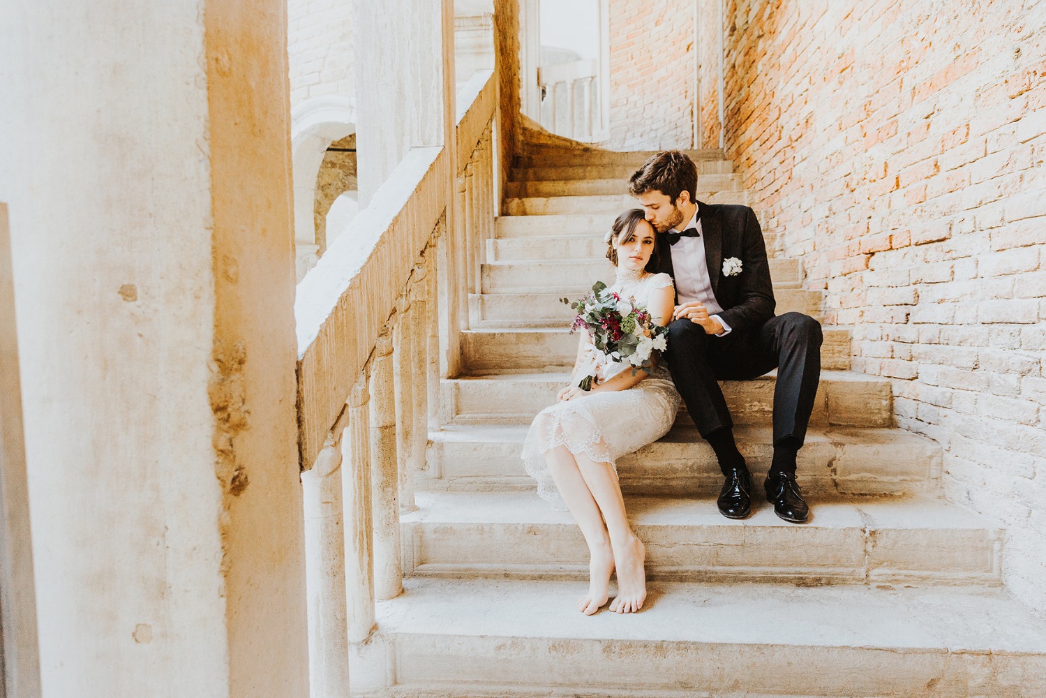 Bride and groom sitting on stone staircase wedding day