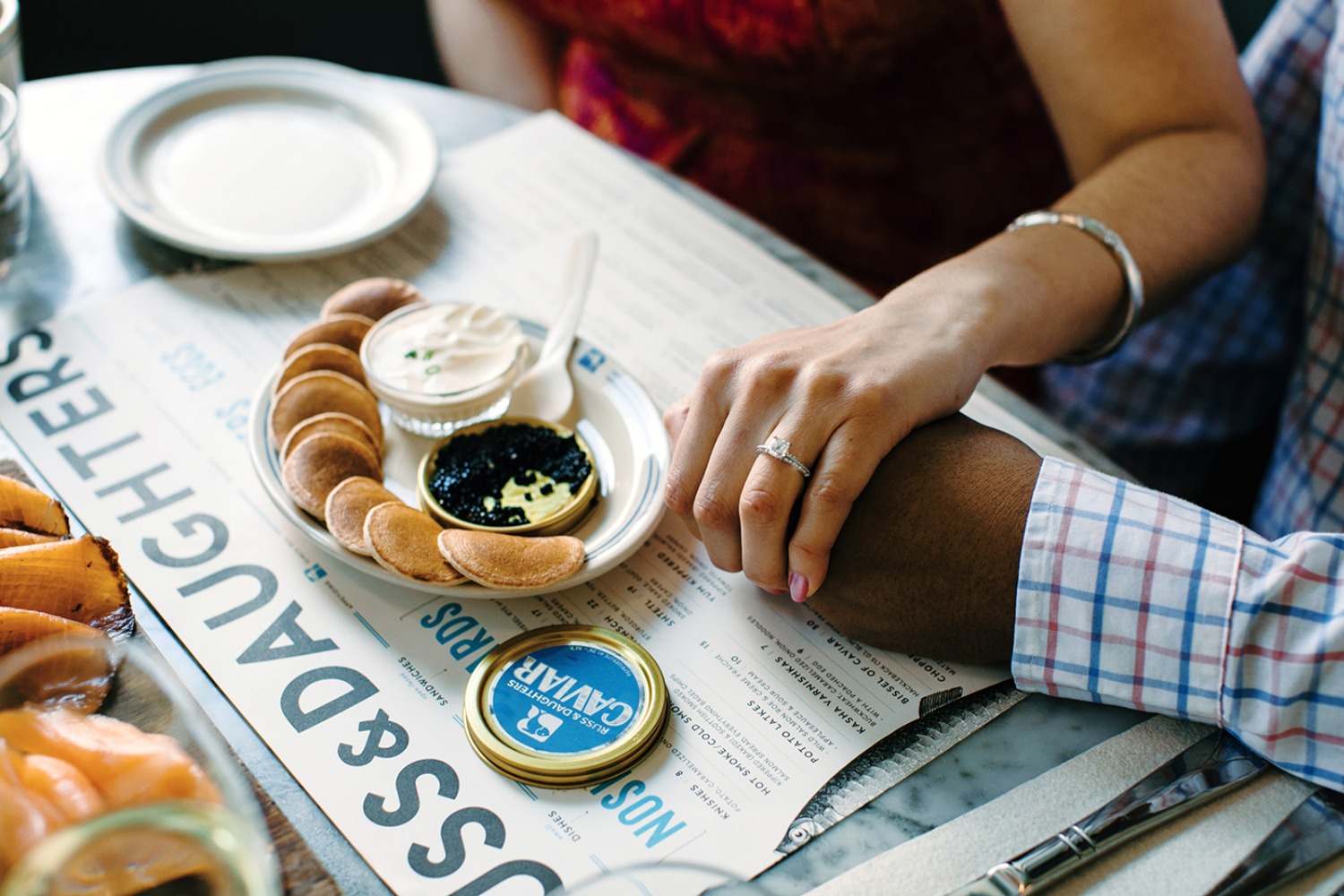 Romantic scene with caviar, blinis, and engagement ring on table