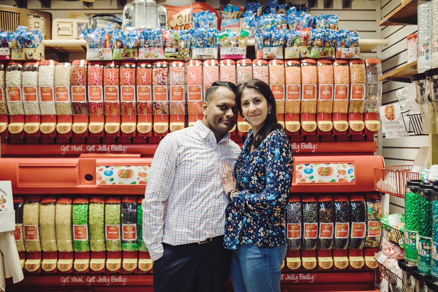 Couple smiles in a candy store with colorful Jelly Belly dispensers