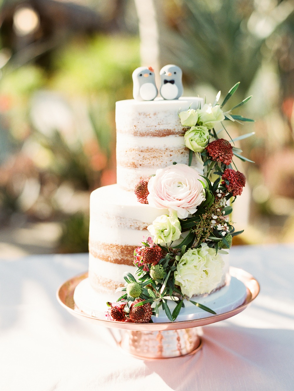 nearly naked wedding cake with penguin toppers