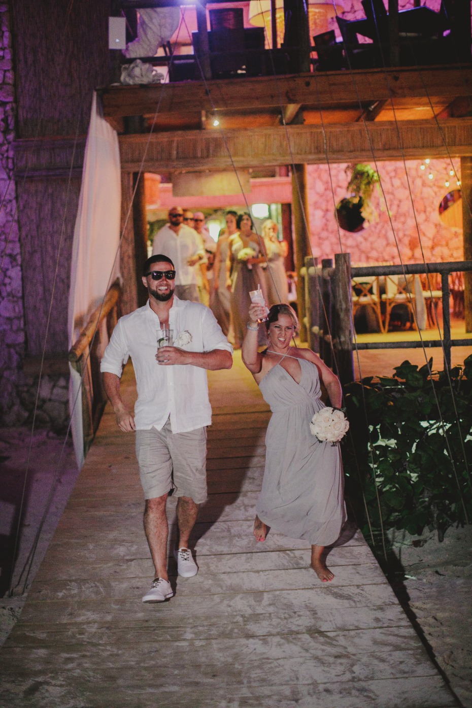 Wedding party celebrates on a wooden bridge at night