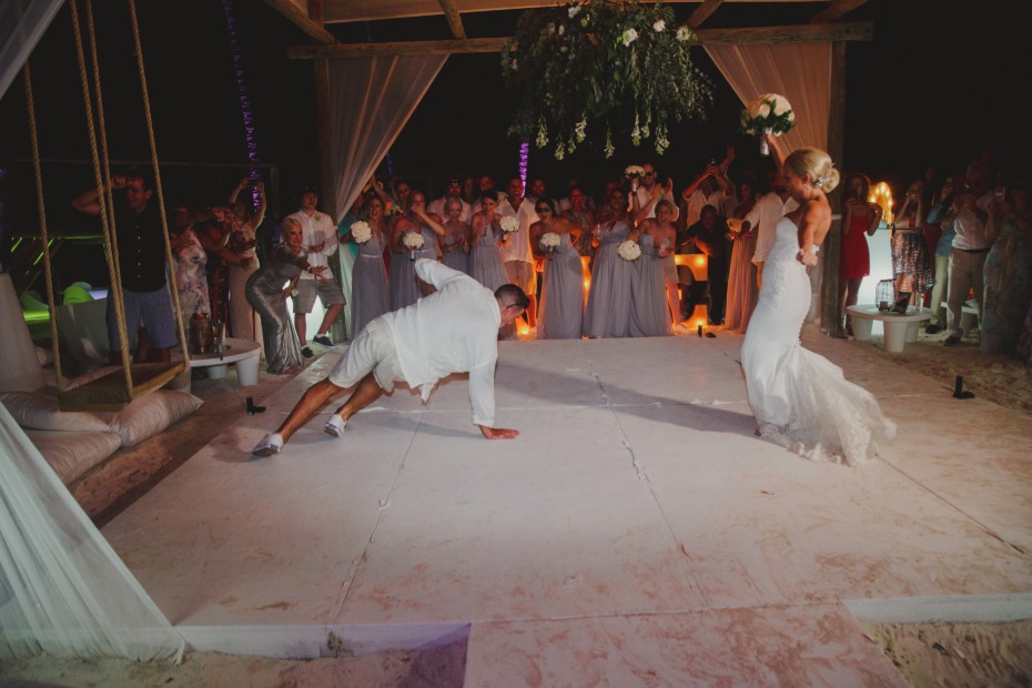 Groom does breakdance at wedding reception, bride smiles and celebrates