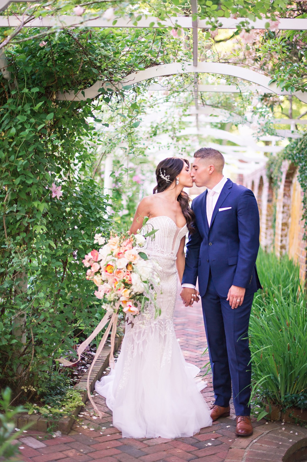 Couple kissing under the archway at a beautiful outdoor wedding