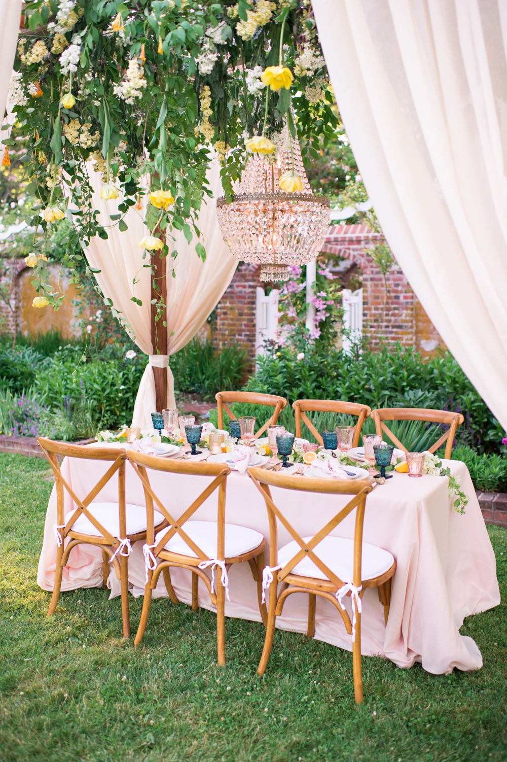 Romantic outdoor wedding reception table setting with floral chandelier