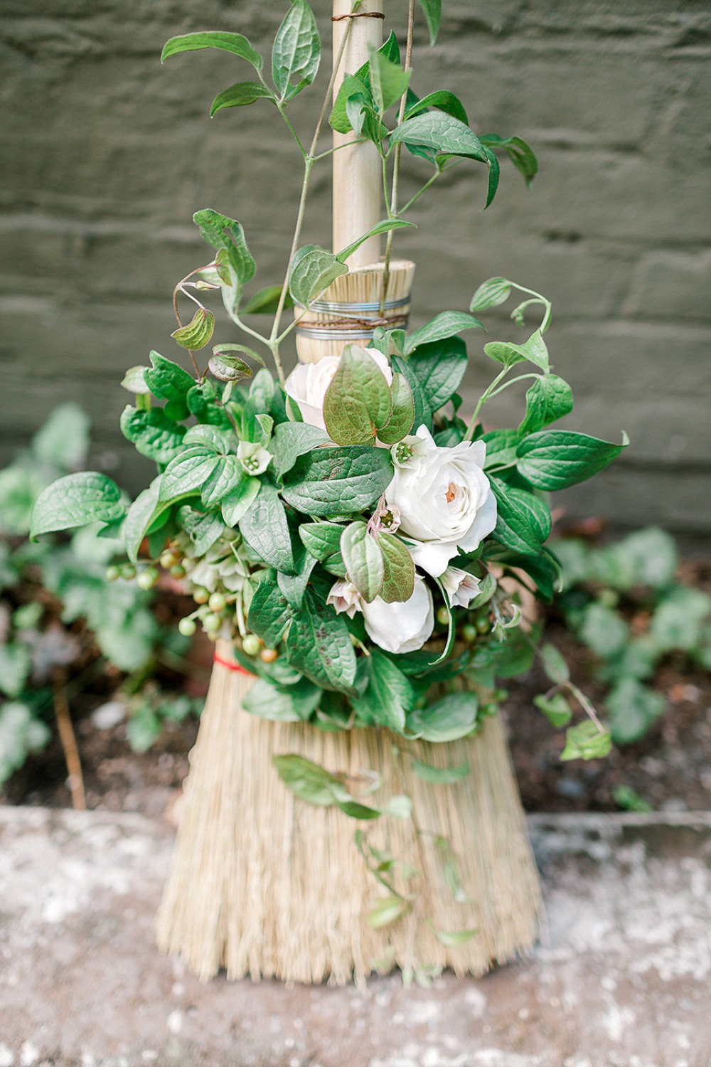 Broom adorned with a bouquet of flowers and lush green foliage