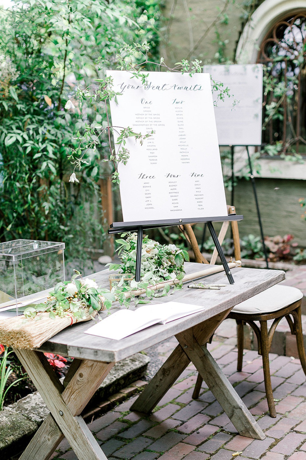 Wedding seating chart displayed on a rustic wooden table outdoors