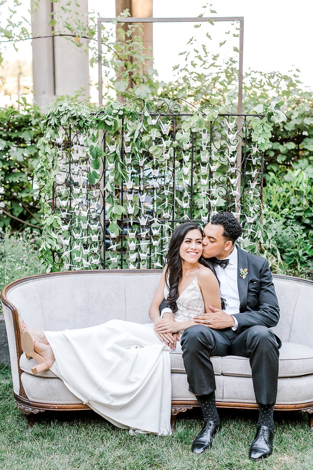 Happy couple in wedding attire on an outdoor sofa, smiling