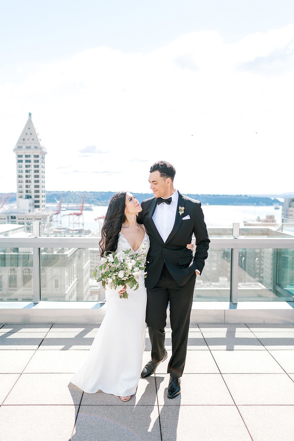 Happy wedding couple poses on rooftop with city view