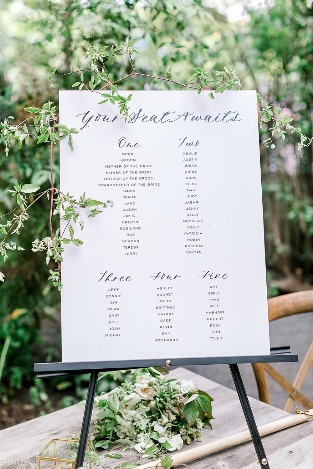 Wedding seating chart with calligraphy details and greenery