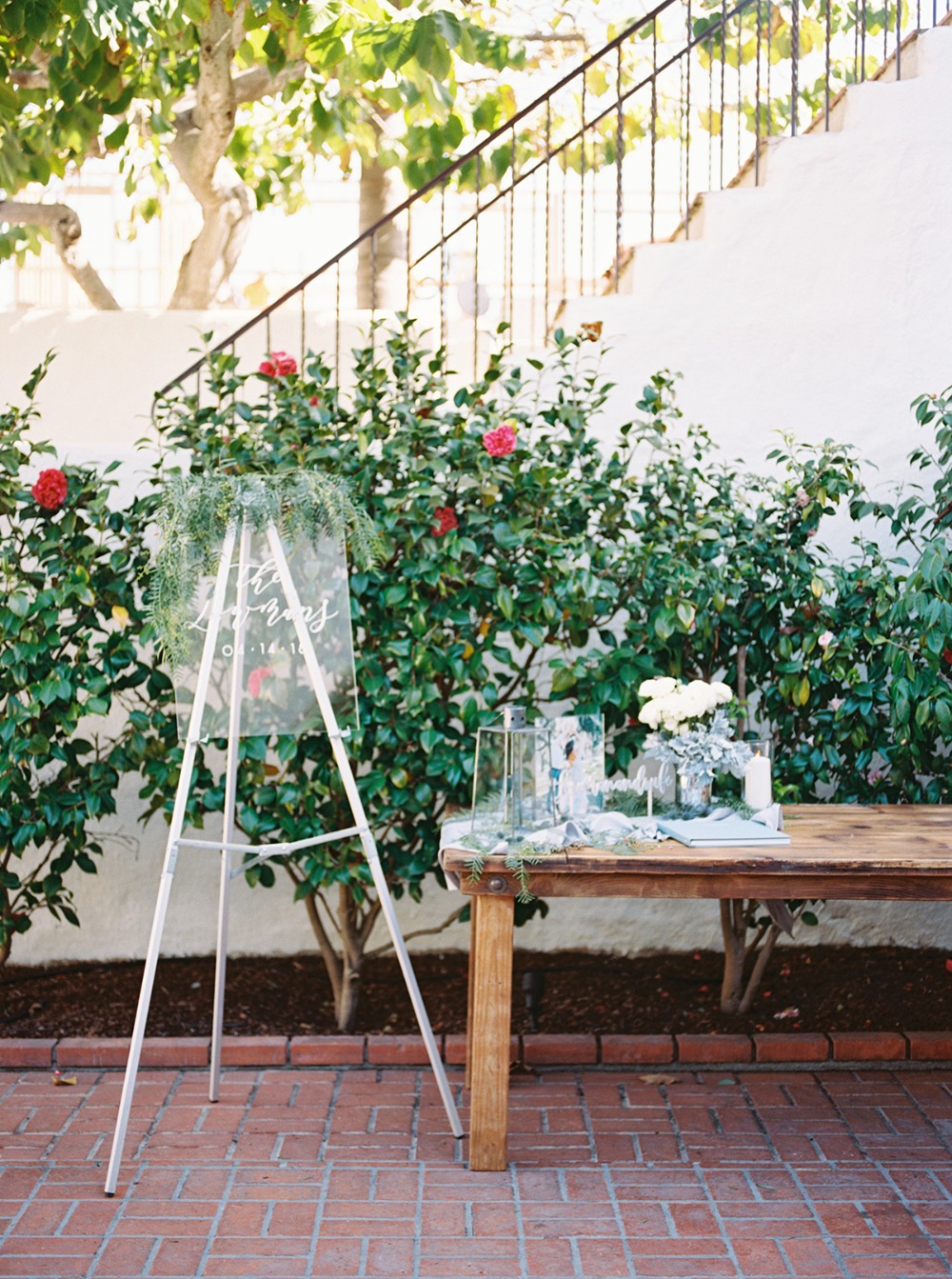 Wedding welcome sign surrounded by greenery and a table