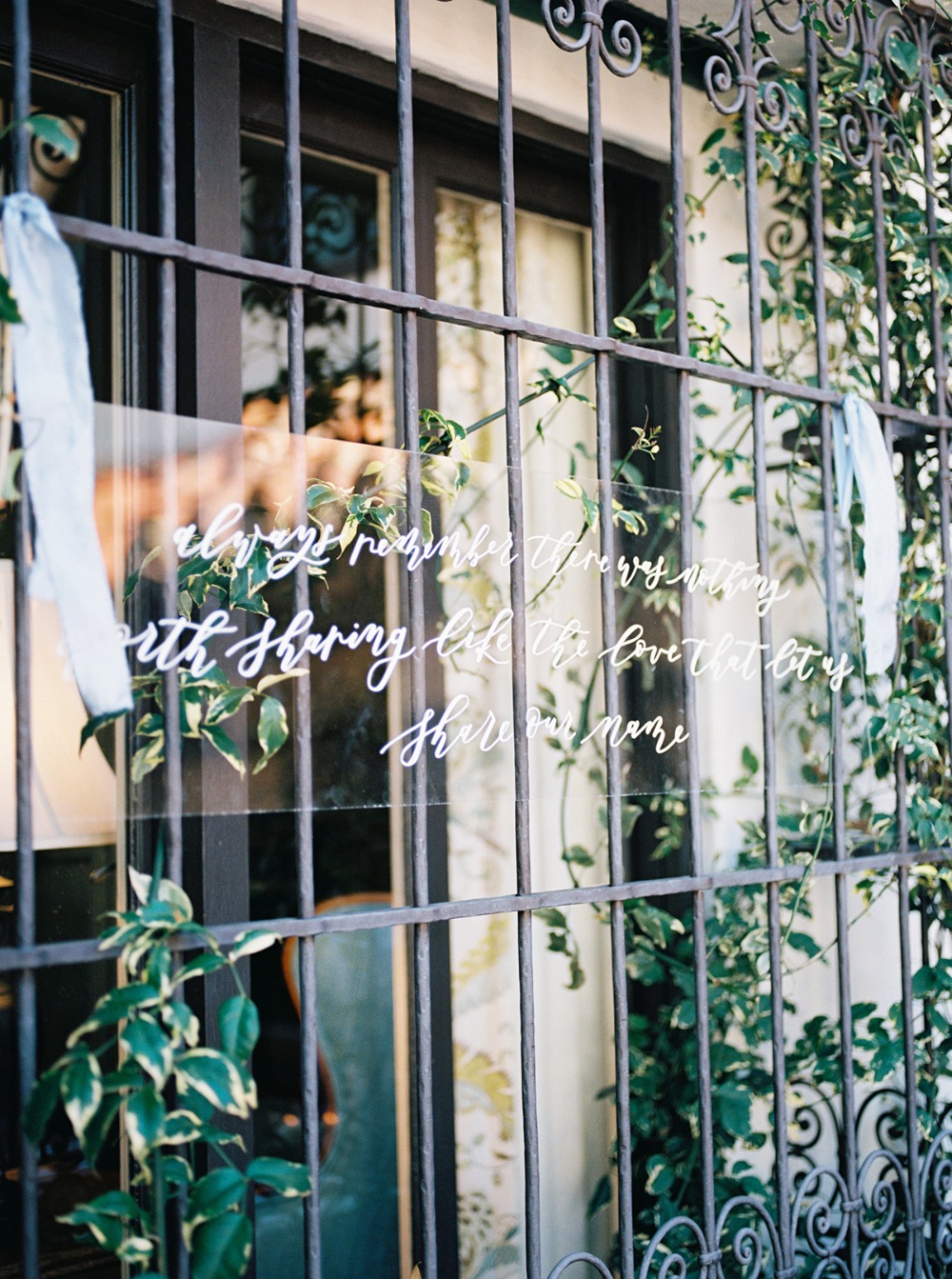 Romantic calligraphy on glass through an ornate wrought iron gate