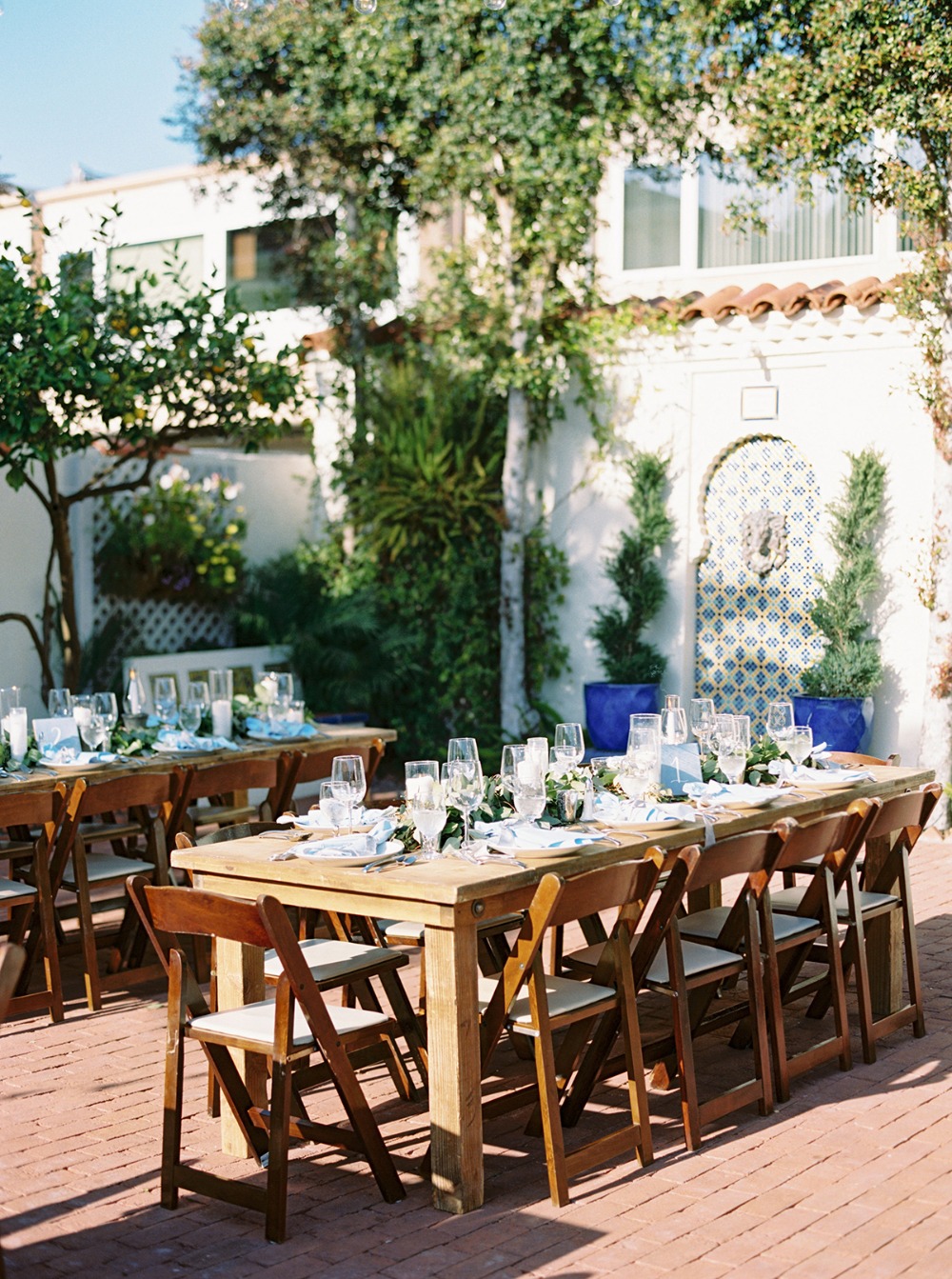 Outdoor wedding reception with wooden tables and chairs