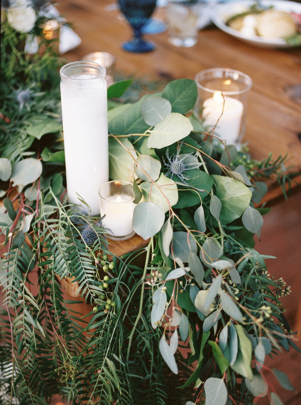 Candles and greenery centerpiece on wooden table