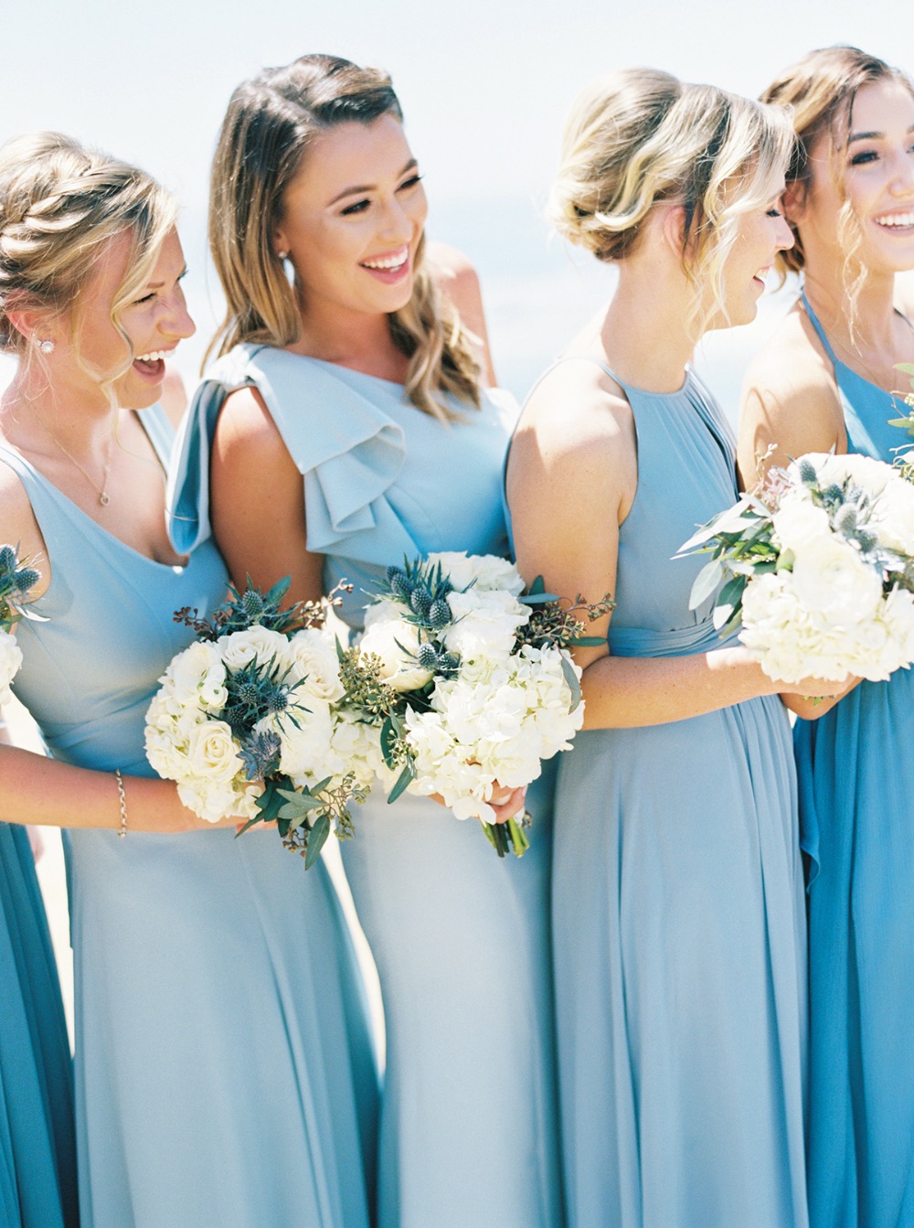 Bridesmaids smiling and holding flowers at an outdoor wedding