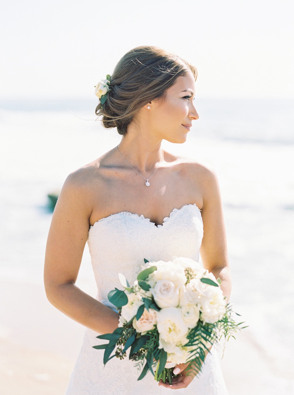 Beautiful bride holding a bouquet at a beach wedding ceremony