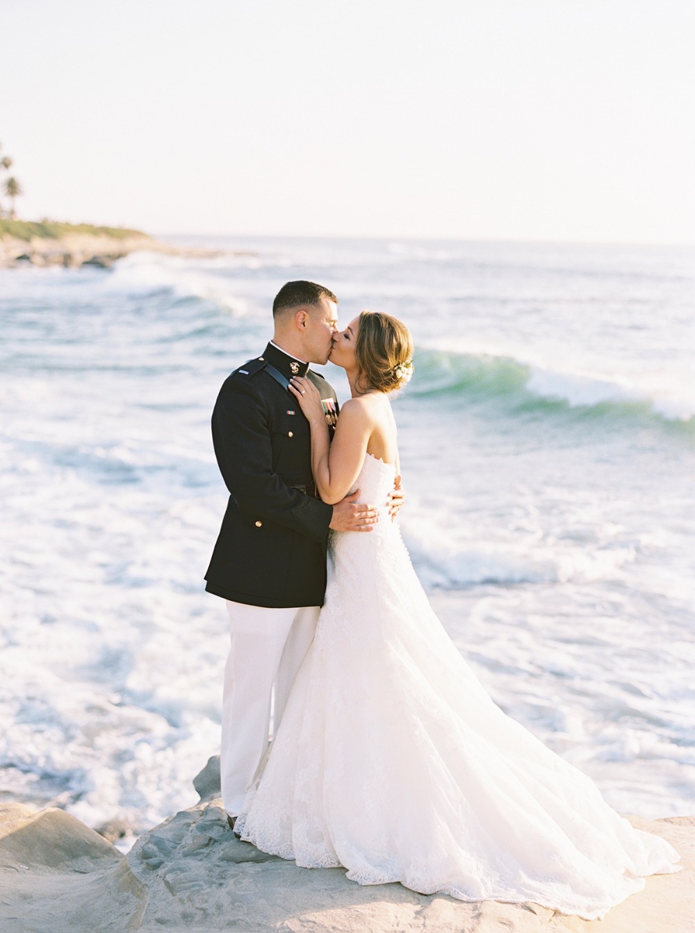 Bride and groom kiss on a beach at wedding ceremony