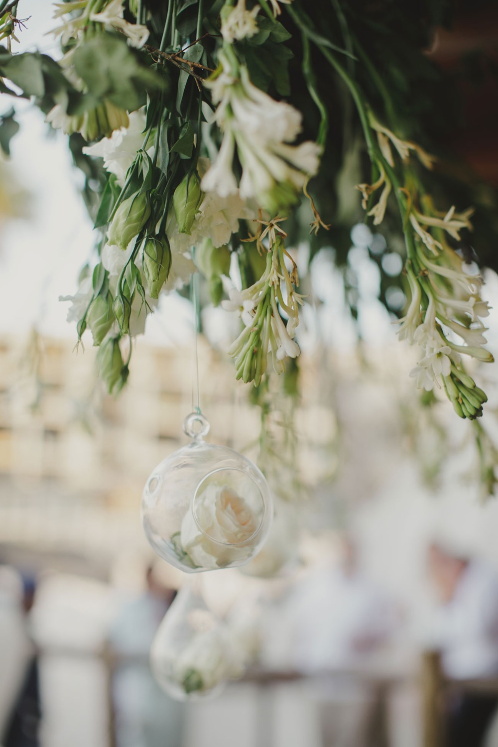Floral arrangement with hanging glass orbs and white roses