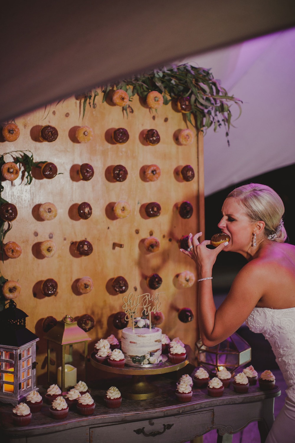 Bride joyfully eats donut from wedding dessert display