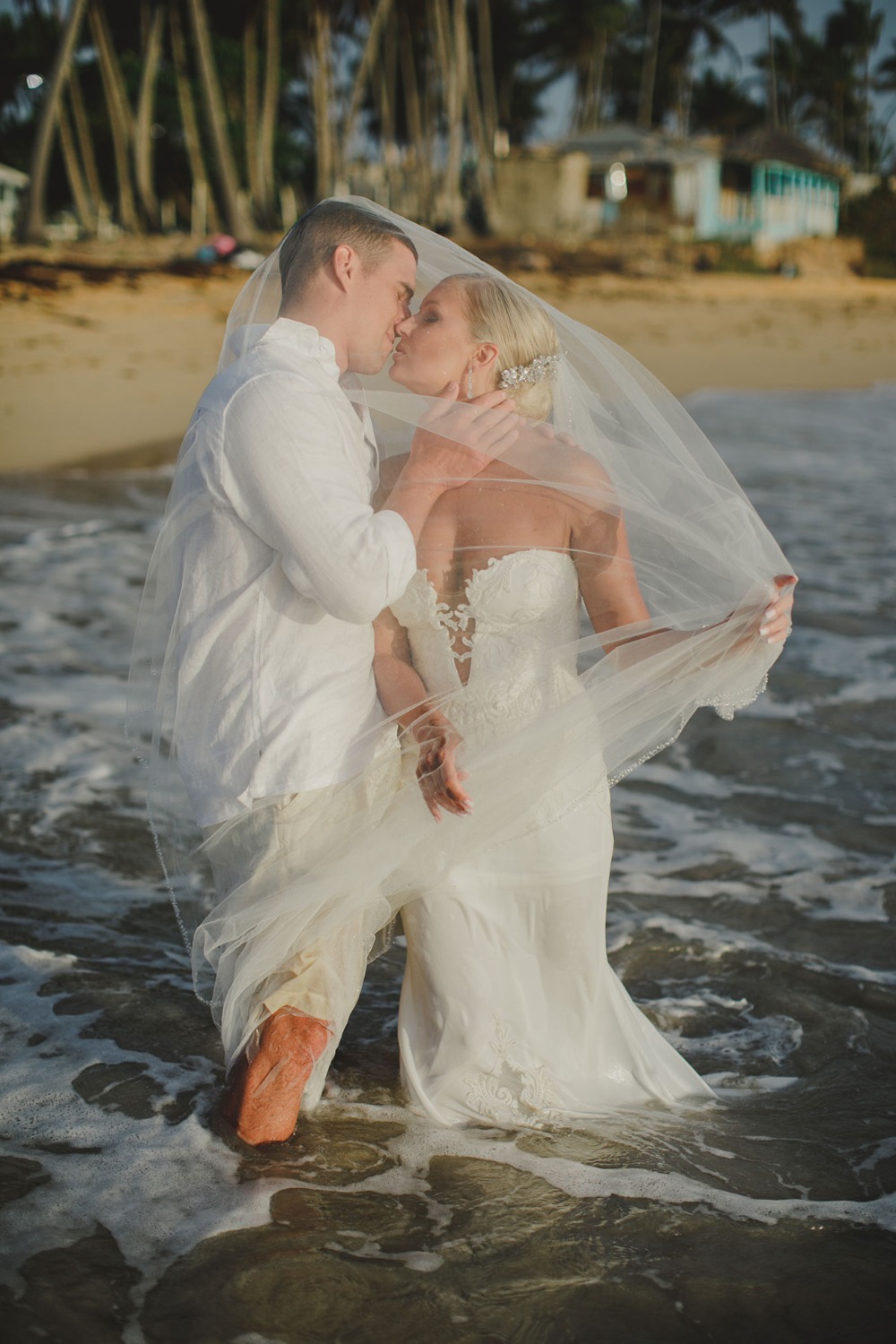 Newlyweds sharing a kiss in the ocean on their wedding day