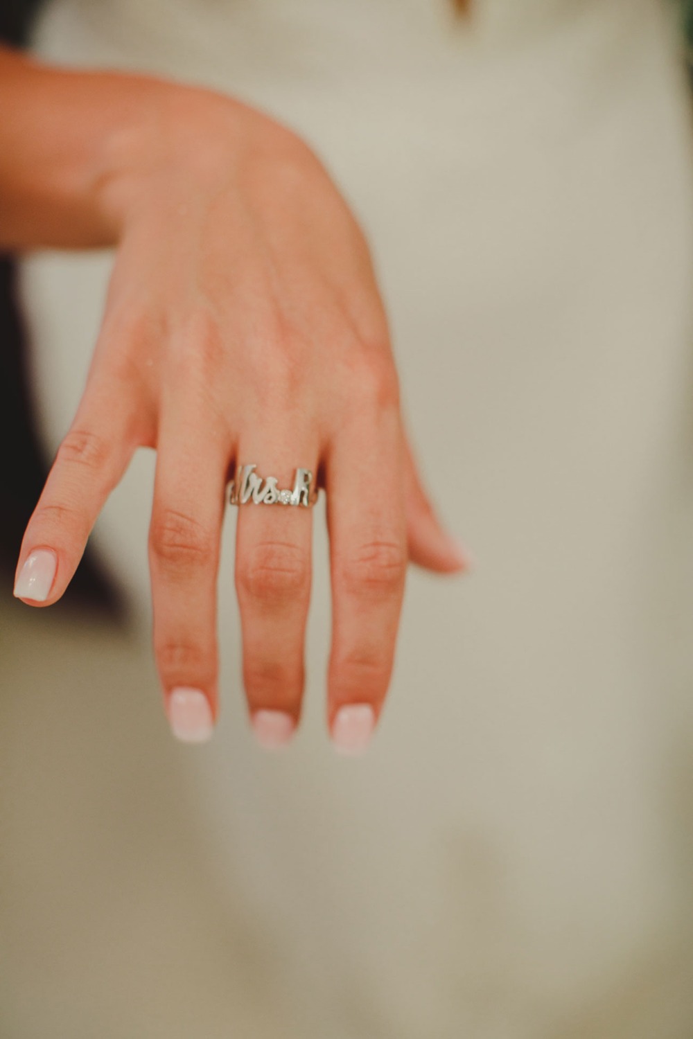 Close-up shot of a hand wearing a Mrs  ring at a wedding