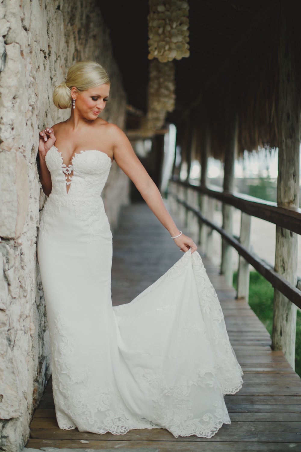 Bride in a beautiful white wedding gown stands elegantly on the boardwalk