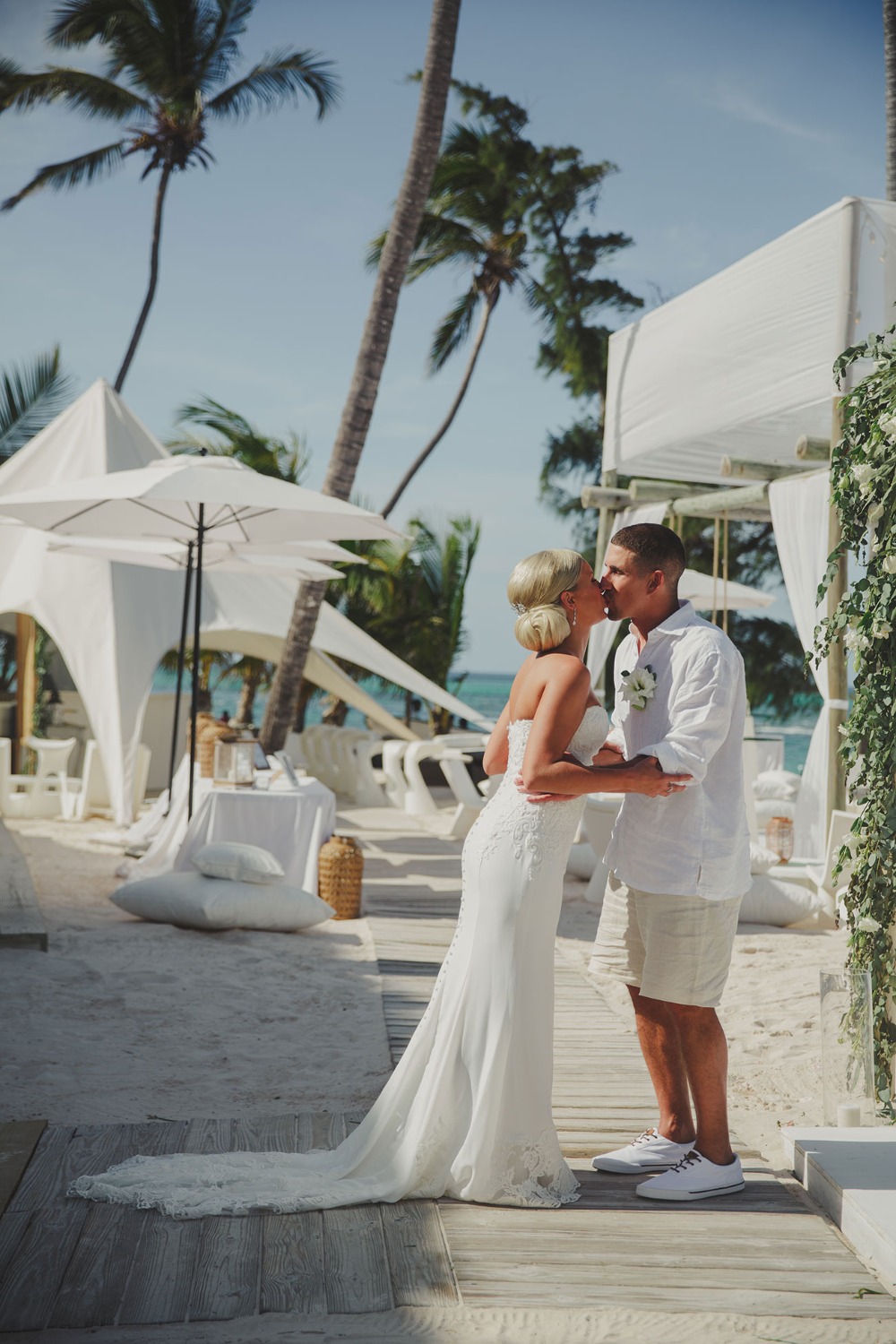 Bride and groom share a kiss on a sunny beach wedding ceremony