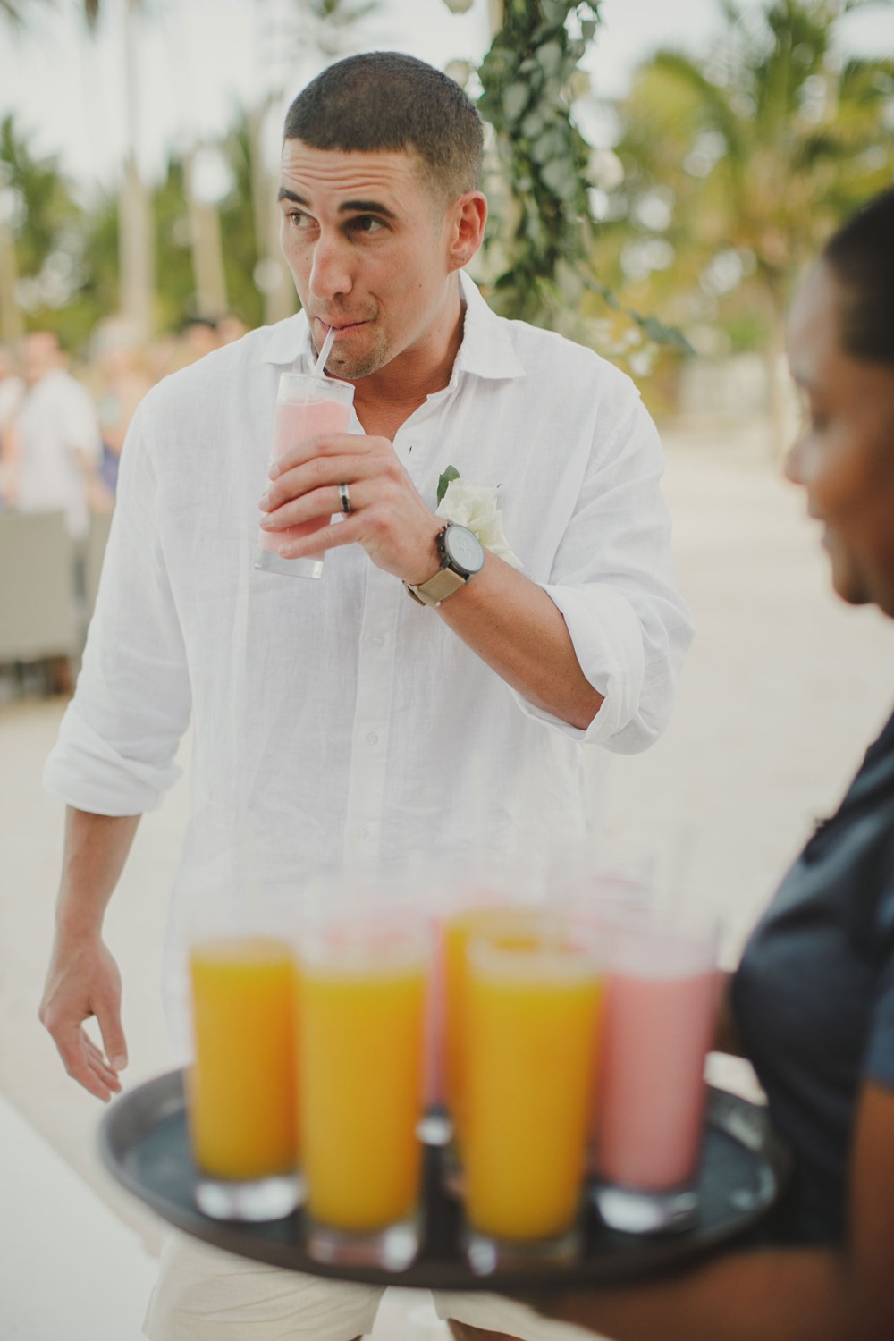 Groom enjoys a refreshing drink at a beach wedding
