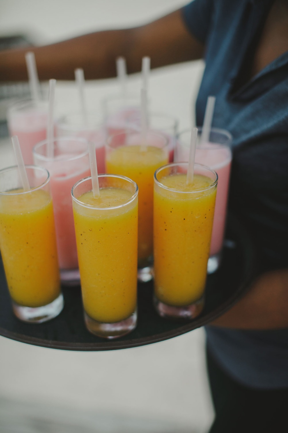 Waiter carrying tray with yellow and pink smoothies
