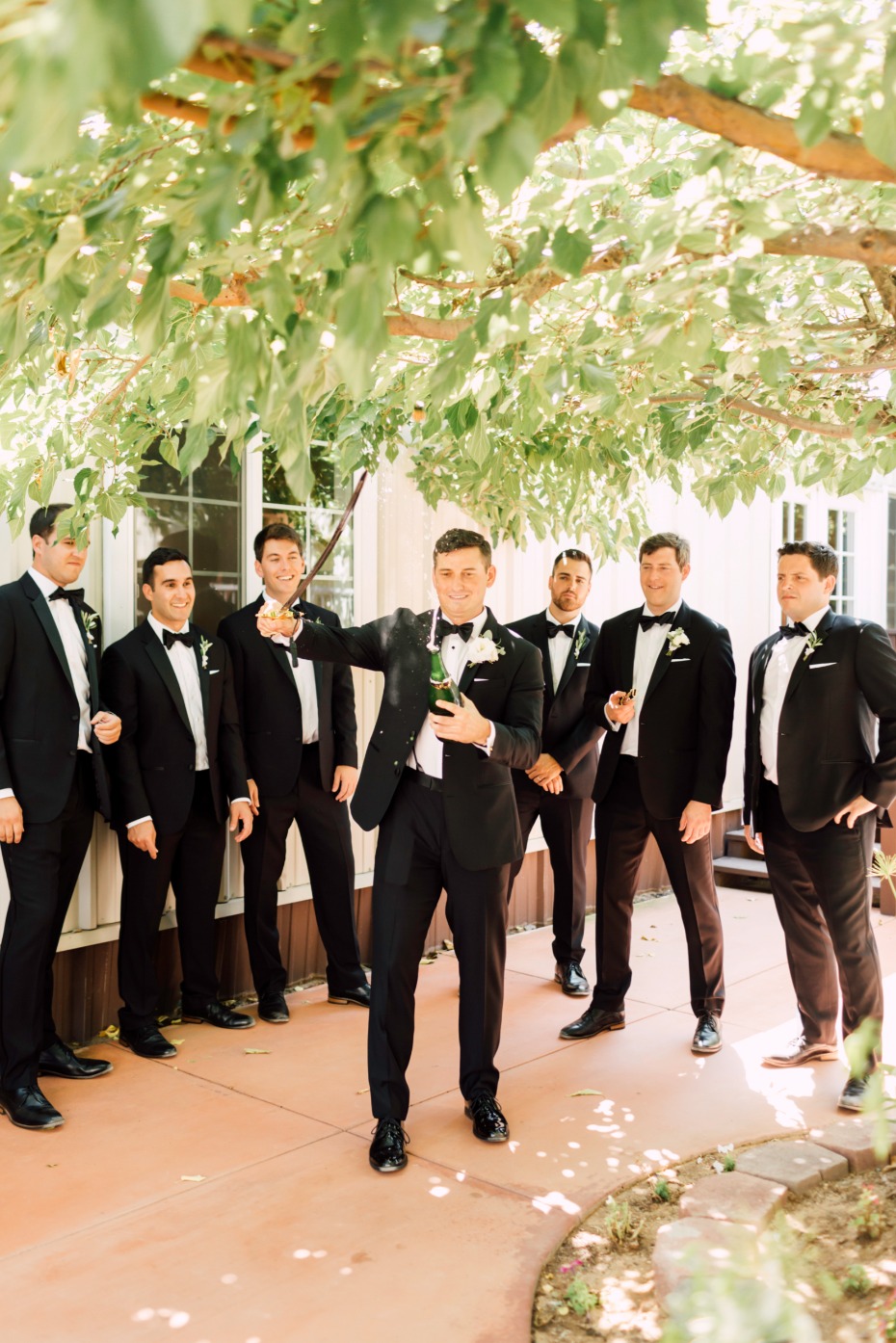 Groom celebrating with groomsmen champagne wedding day