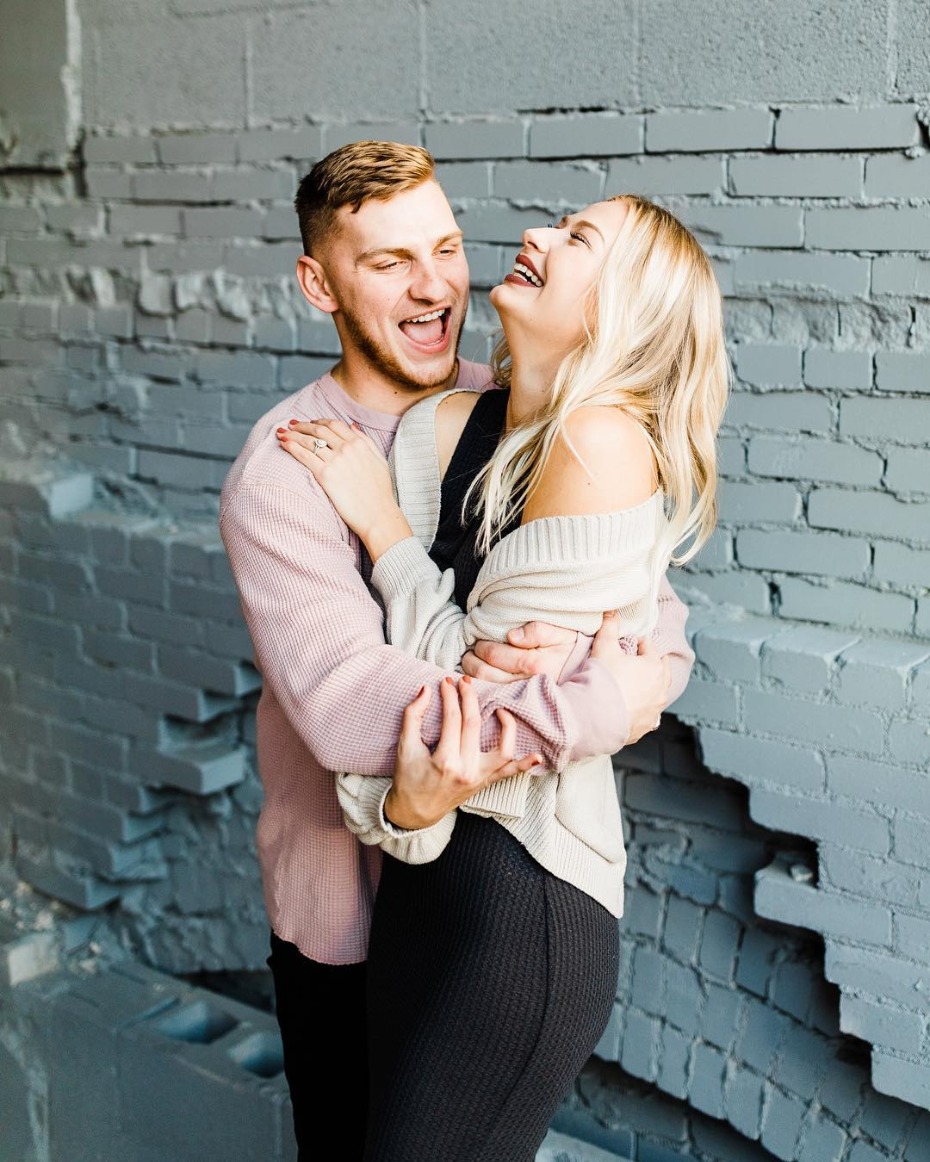 Couple laughing embracing against a brick wall background