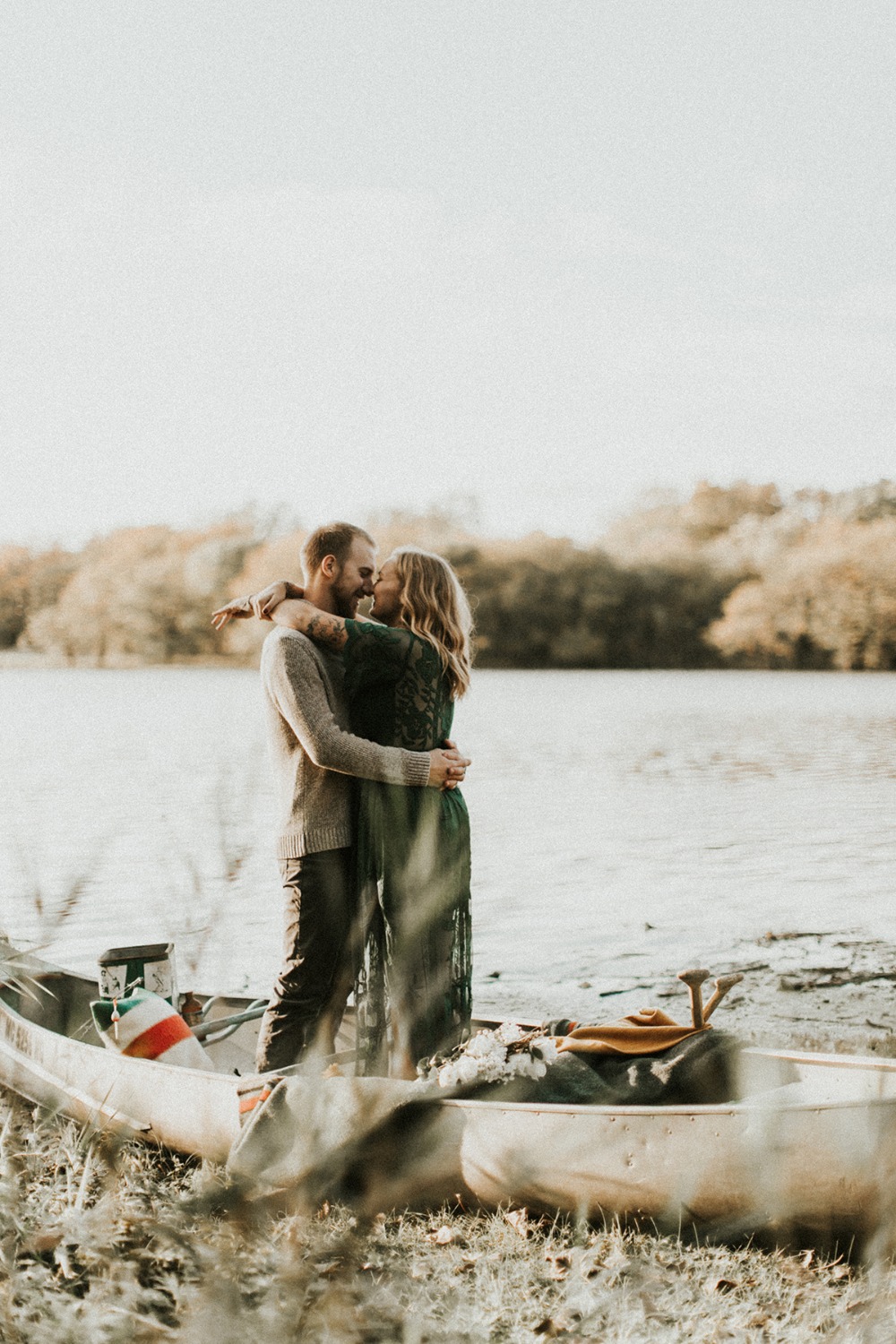Outdoor couple embracing romantically by canoe lake