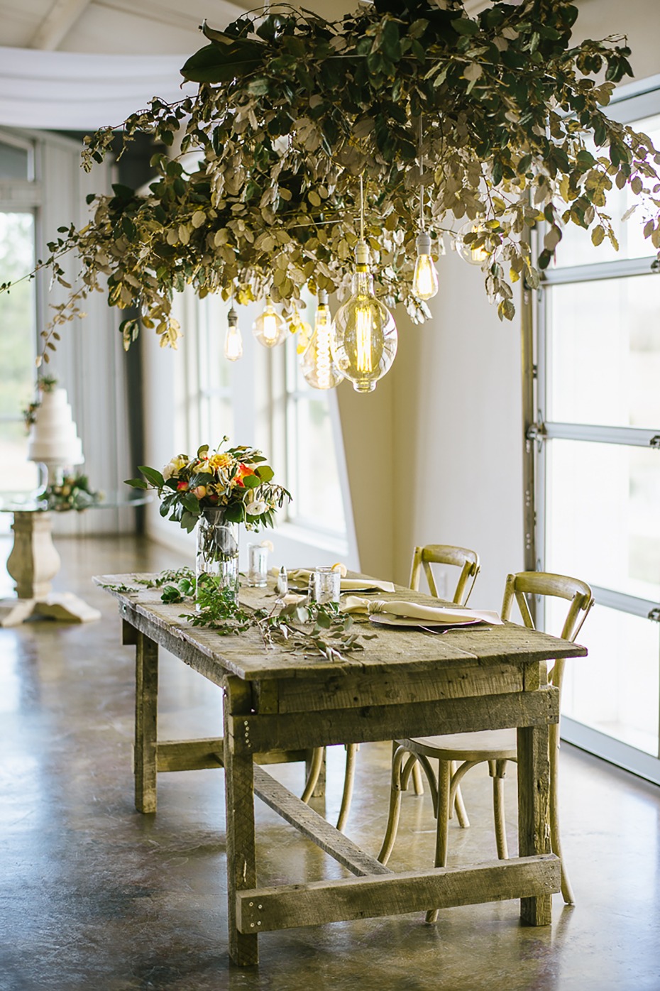 Sweetheart table with greenery and hanging bulbs