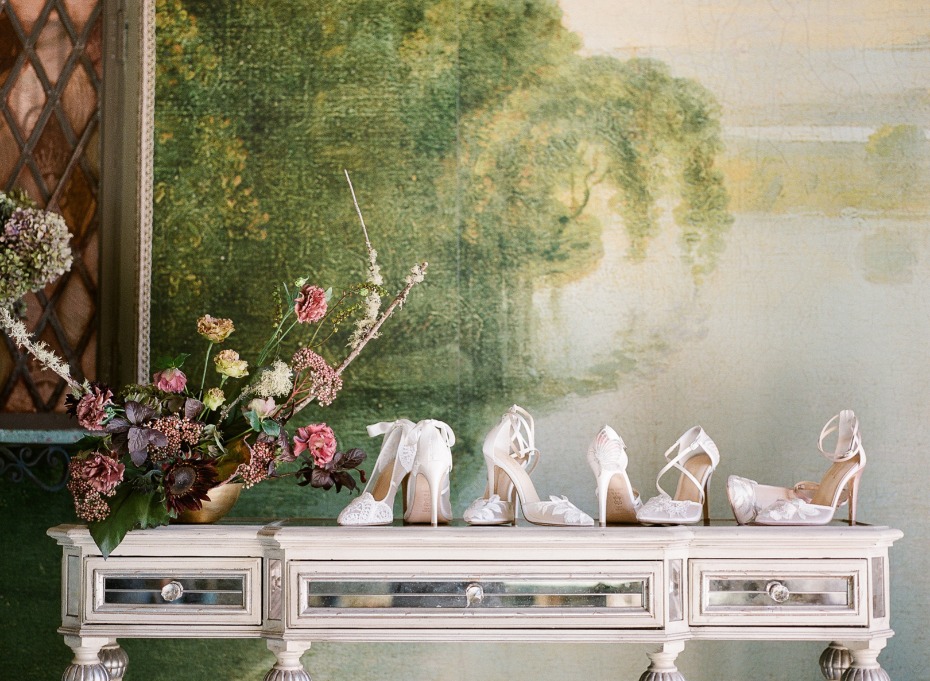 Elegant wedding shoes on mirrored table with flowers