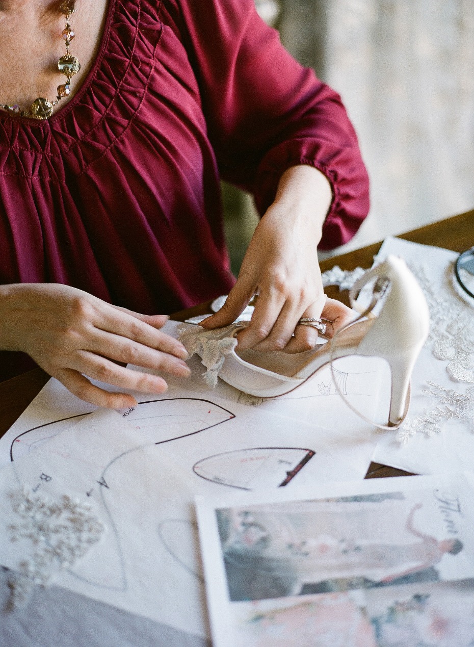 Woman embellishing a white wedding shoe with lace