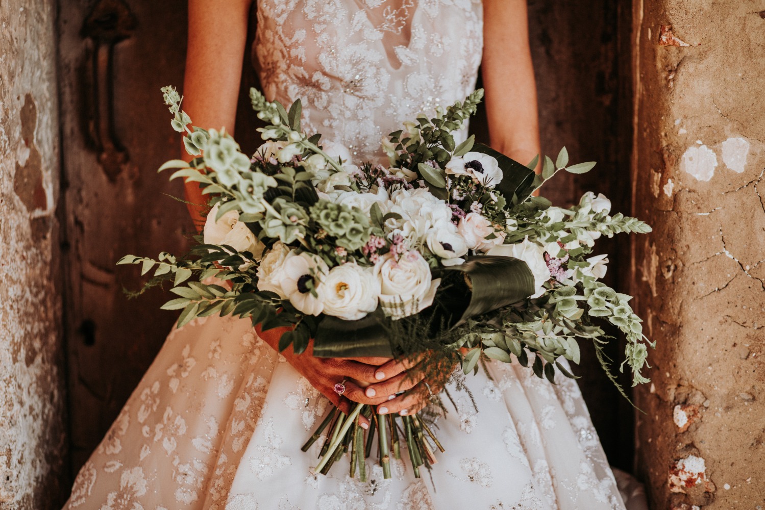 Bride in white dress holds wedding bouquet, closeup shot