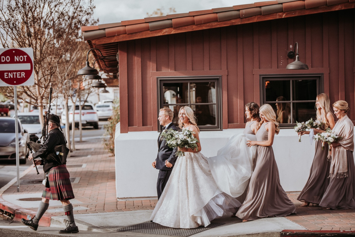 Bride walks with bagpiper and bridesmaids on her wedding day