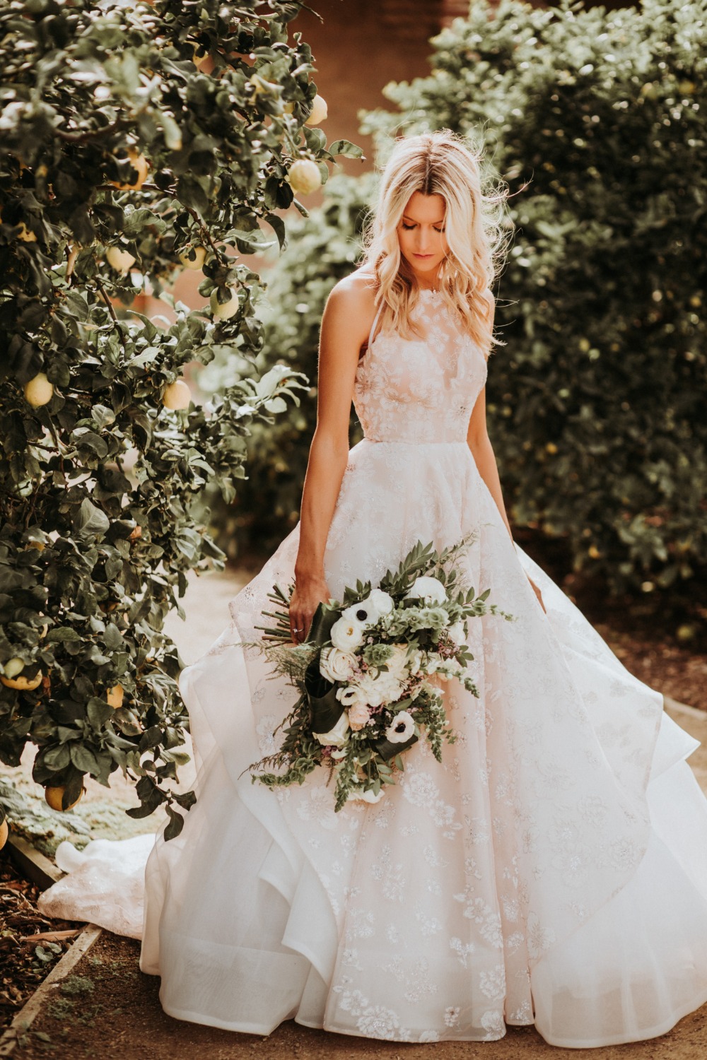 Bride in lace gown holding bouquet in garden setting