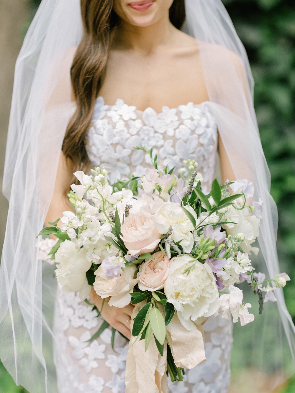 Bride in gown holds white and blush floral bouquet
