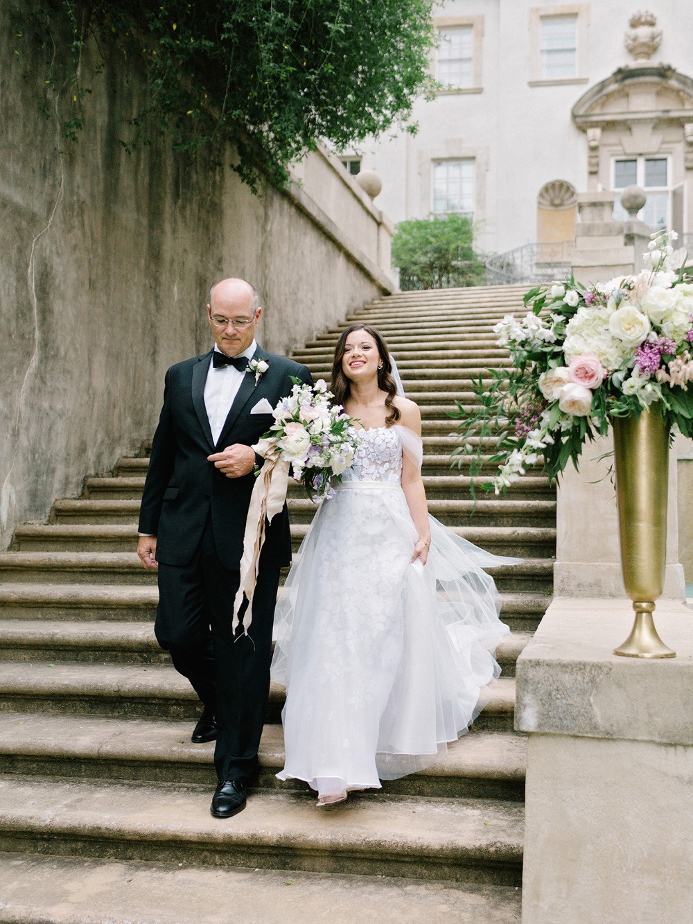 Bride with father walking down stairs at wedding