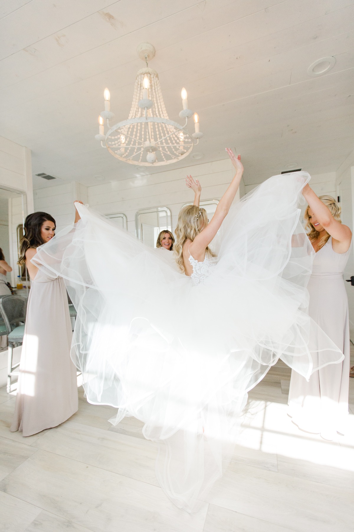 Bride and bridesmaids celebrate with wedding dress in a bright room