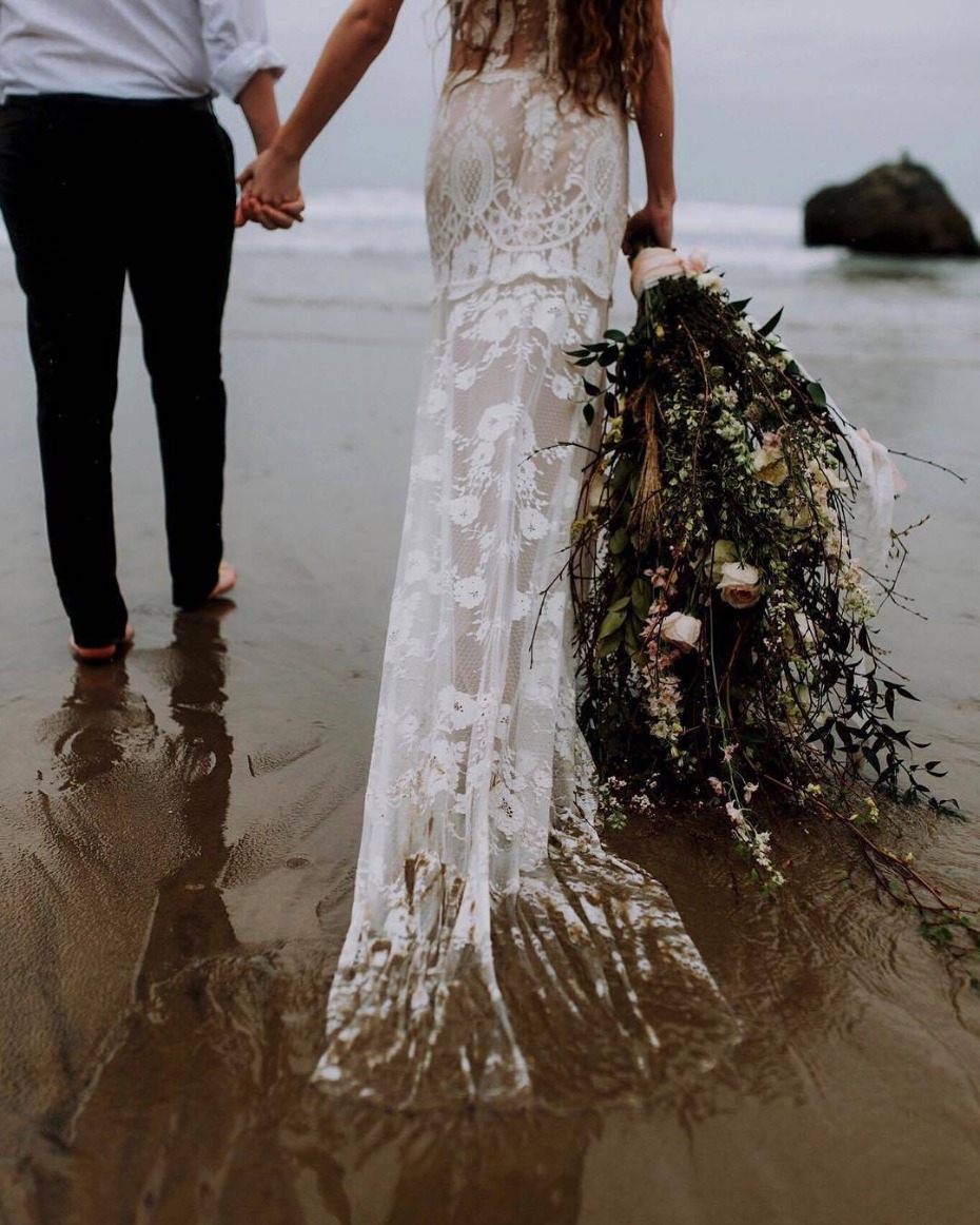 Bride holding a huge bouquet as she walks into the ocean
