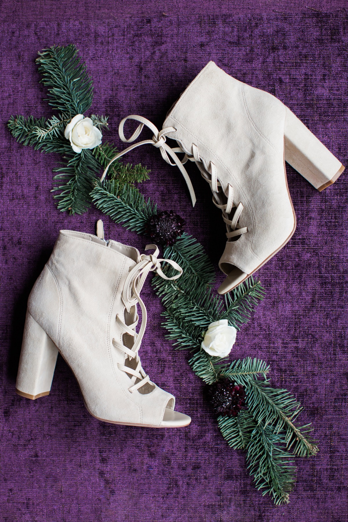 Beige lace-up heeled boots with floral decor on a purple background
