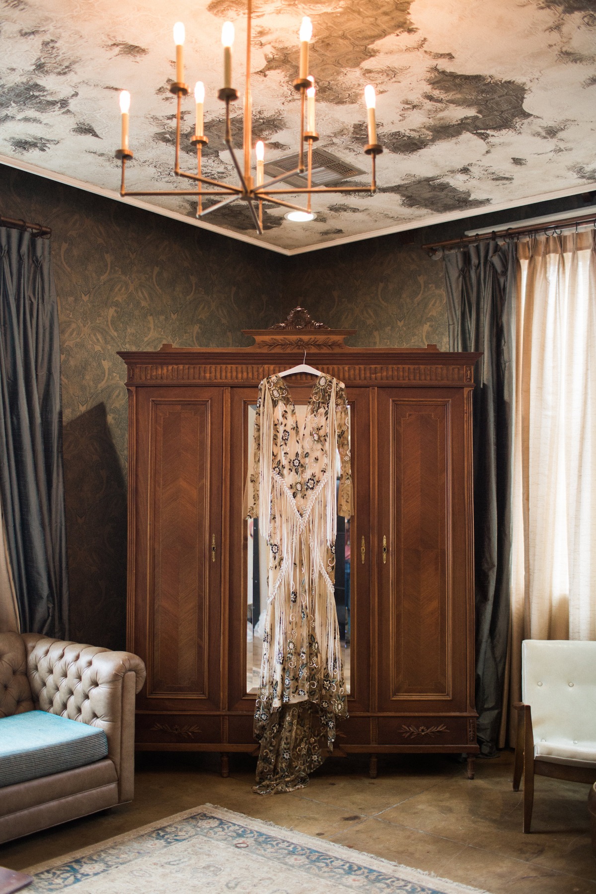 Elegant wedding dress hanging in a vintage style room with chandelier