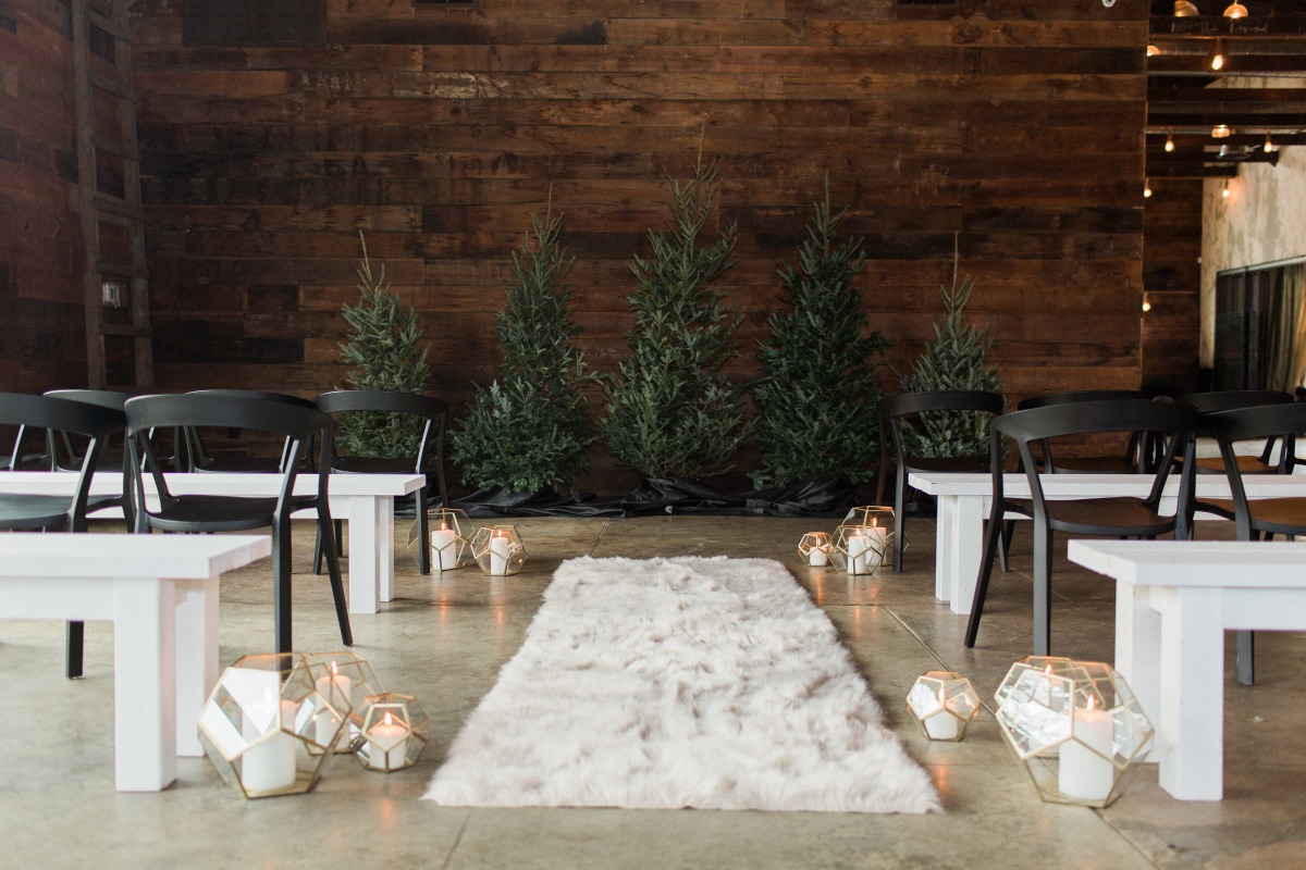 Cozy wedding aisle decor with trees, candles, and a fluffy rug