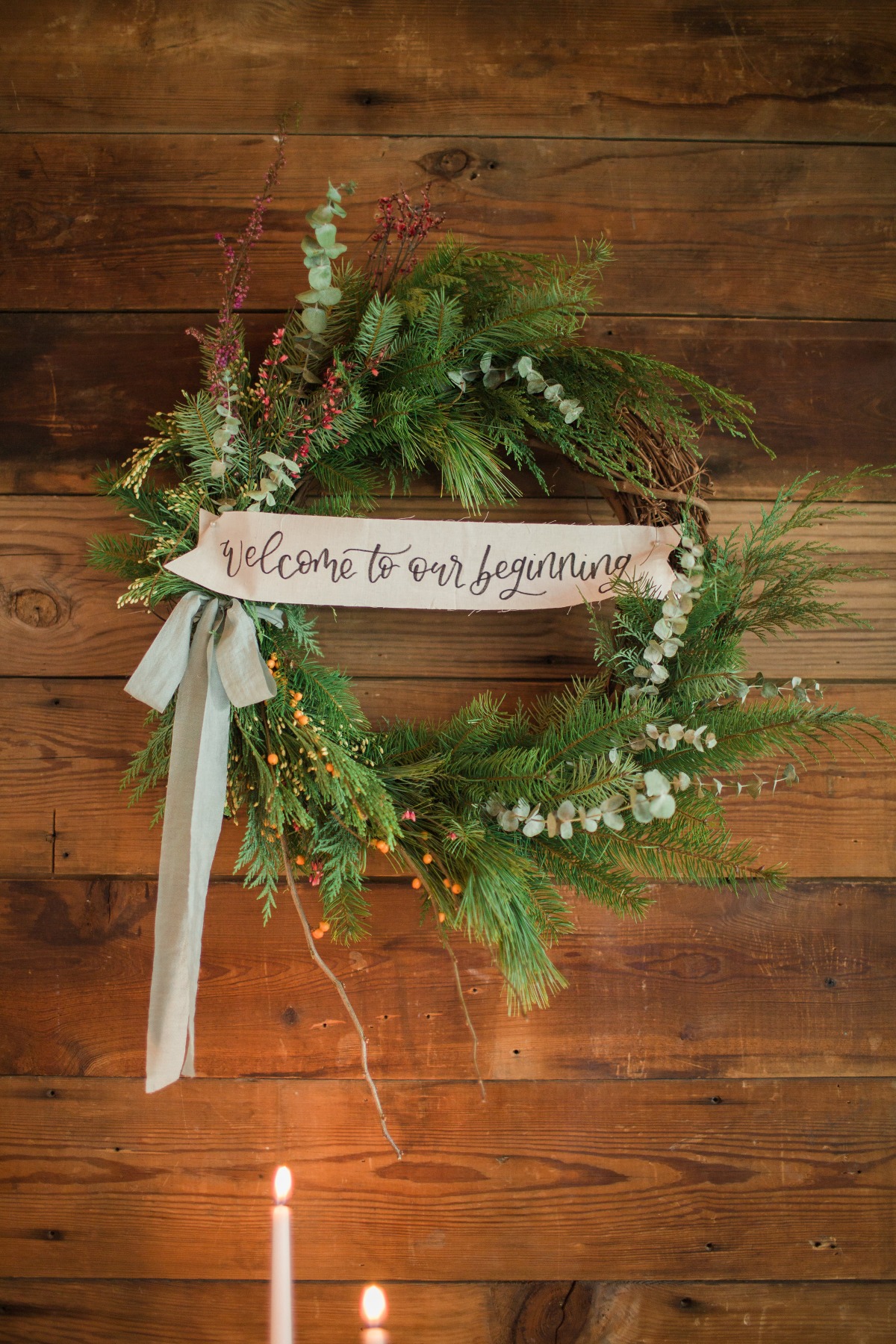 A beautiful welcome wreath with candles on a wooden wall